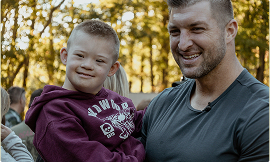 Tim Tebow holding a child