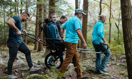 Tim Tebow and friends helpinjg a boy explore the woods