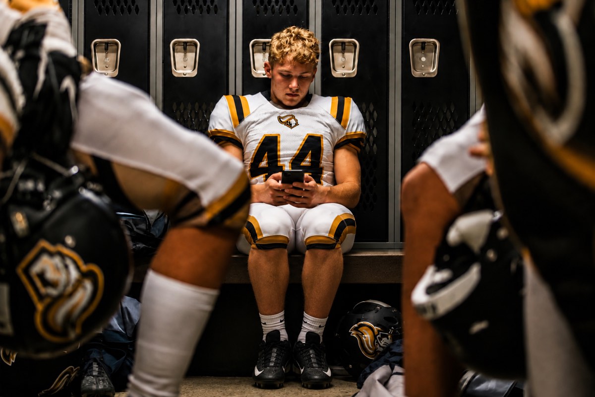 Student looking at his phone in a locker room